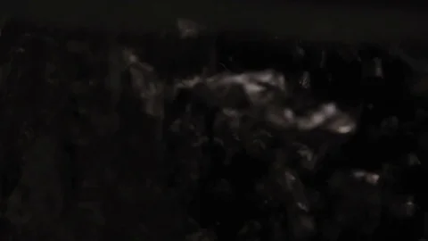 The water flows closeup and lots of bubbles on a black background in slow motion Stock Footage