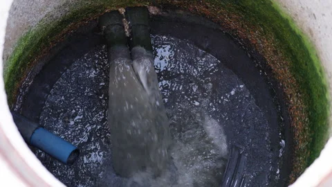 Water flows continuously from pipes into a dark, murky sewerage tank, showcasing Stock Footage 319538002