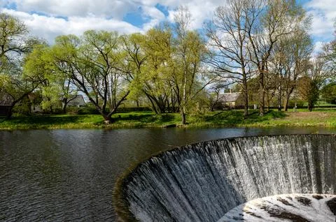 Water flows from a dam on the river. Spring in the village. Zagare, Latvia Stock Photos