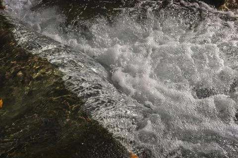 Water flows down and foams white foam in the river Foto stock