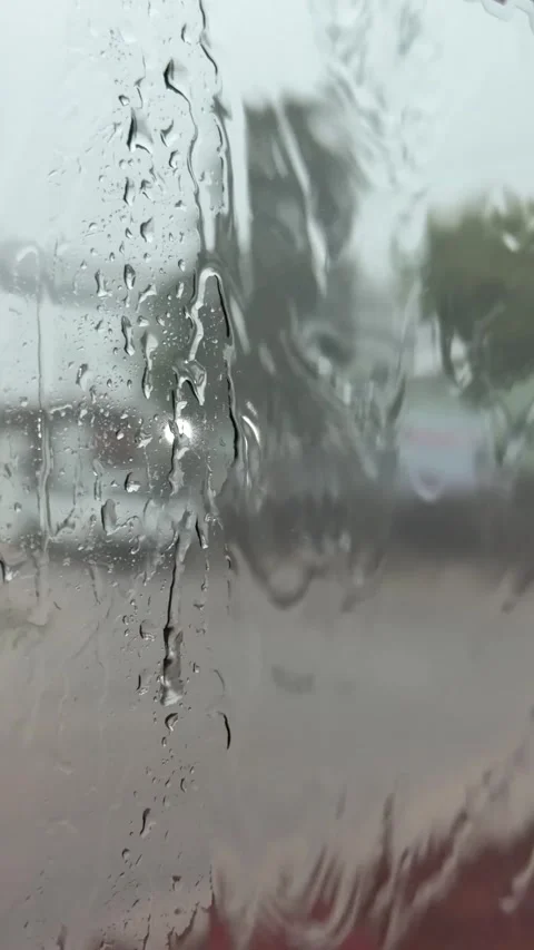 Water flows down a bus window with a roadway and street elements visible beyond Stock Footage 339279912
