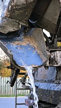 Water flows down the chute of a concrete mixer. Washes the concrete mixer after Stock Photos