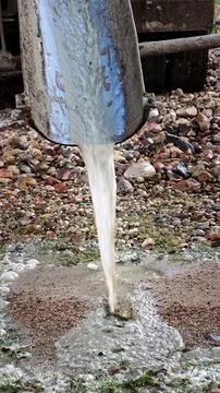 Water flows down the chute of a concrete mixer. Washes the concrete mixer after Stock Photos
