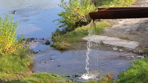 Water flows down a metal gutter into a river. Stock Footage 114505102