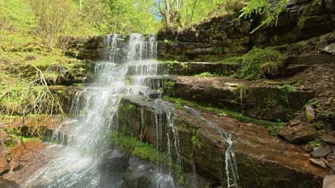 Water flows down mossy stone steps. Slowmotion. Tupavica Waterfall Vídeos de archivo 335536145