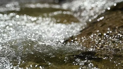 Water flows down in the mountains in the sunlight (slow motion, hexagonal bokeh) Stock Footage 219640312