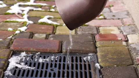 Water flows down a plastic drain pipe from a roof after snow melts in spring Stock Footage 306090807