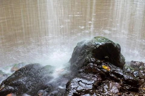 Water flows down from the rock onto the rocks Stock Photos