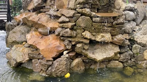 Water flows down the rocks into the pond. Stock Footage 195520780