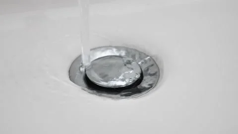 Water flows down in sink drain hole. slow motion water drain in ceramic sink Video stock 233292178