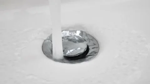 Water flows down in sink drain hole. slow motion water drain in ceramic sink Stock Footage 234428319