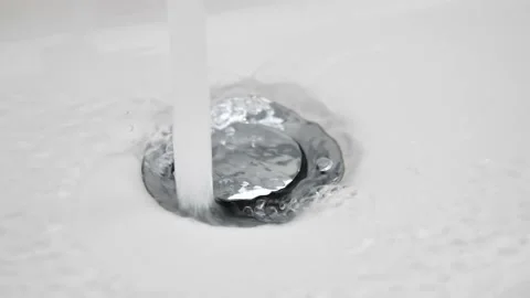 Water flows down in sink drain hole. slow motion water drain in ceramic sink Stock Footage 237027975