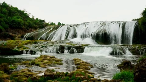 Water flows down a wide waterfall with green moss Stock-Footage 333815949
