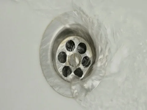 Water flows into the drain hole in the white sink Видео 84853178