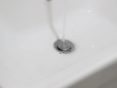 Water flows into drain in white sink Stock Footage 125802387