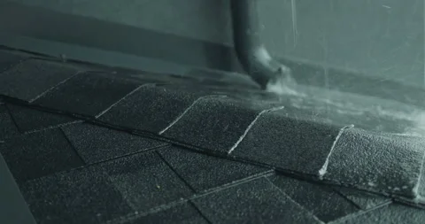 Water flows from a drainpipe onto a shingle roof. Heavy rain Stock Footage 249473786