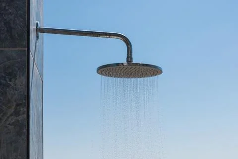 Water flows elegantly from a modern showerhead, providing a refreshing expe.. Stock Photos