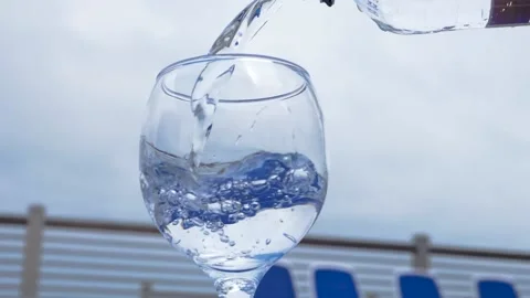 Water flows into a glass next to the pool in slow motion. Healthy lifestyle. Stock Footage 155224780