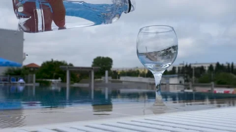 Water flows into a glass next to the pool in slow motion. Healthy lifestyle Stock Footage 155224801