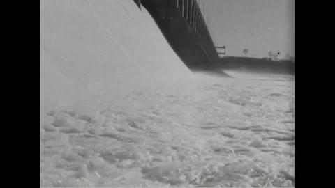 Water flows with great speed over flood gates of a dam - 1940 Stock Footage 101727293