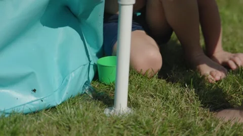 Water flows from hole in blue inflatable pool creating refreshing water stream Stock Footage 268342626
