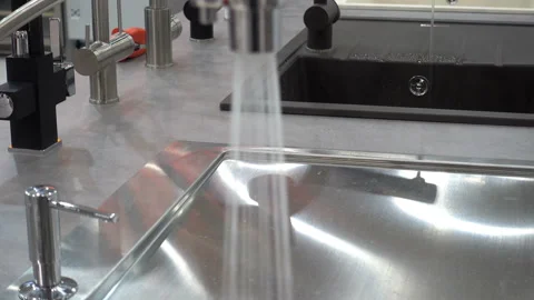 Water flows from a kitchen faucet into a sink in 4K Stock Footage 128224341