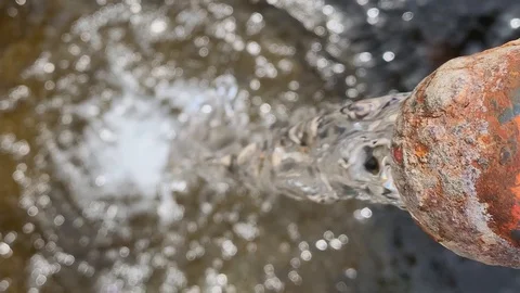 Water flows from an old rusty well into the pool of water from above Stock Footage 108537846