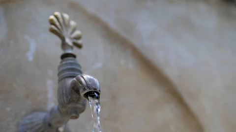 Water flows from an old stone crane in oriental style. close-up Stock Footage 124689231