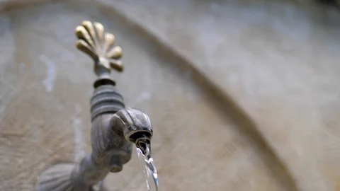 Water flows from an old stone crane in oriental style. close-up Stock Footage 124689292
