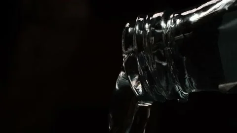 Water flows out of the bottle on a black background to the last drop Stock Footage 172568469