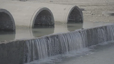 Water flows out of the pipes of the dam into the lake Stock Footage 306675982