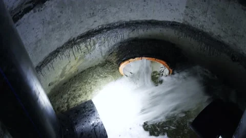 Water flows out of sewer pipe. Media. Inside sewer pit, water flows through Stock Footage