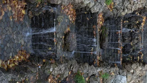 Water flows over an artificial waterfall in the park. Vertical video. Stock Footage 142650891