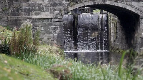 Water flows over canal lock under old bridge, Grand Canal, Dublin Ireland. Stock Footage 102585931