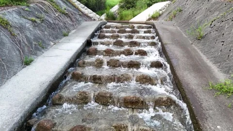 Water flows over concrete steps in a narrow channel Vídeo Stock 343258678