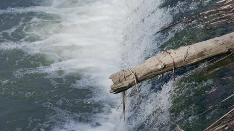 Water flows over a river weir forming a small waterfall with foam and aerat.. Stock Footage 332442914