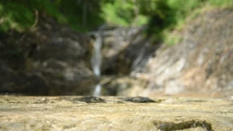 Water flows over rocks in front of a waterfall in summer (slow motion) Stock-Footage 212747106
