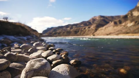 Water flows over rocks by mountains under a cloudy sky Stock Footage 272212209