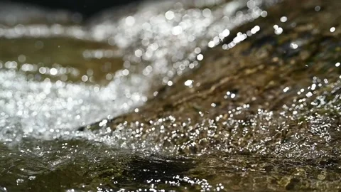 Water flows over rocks in the sunlight (slow motion, hexagon bokeh) Stock-Footage 219640310