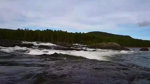 Water flows over rocks at a waterfall in Norway with trees and hills in the.. Stock Footage 340215010