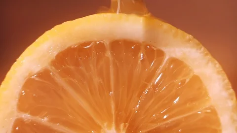 Water flows over a slice of orange. On a warm background. Macro Shot Healthy Stock Footage 127852691
