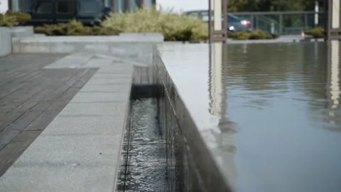 Water flows from overflowing outdoor decorative pool into gutter. Stock Footage 184042020