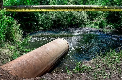 Water flows from the pipe into the river. Stock Photos