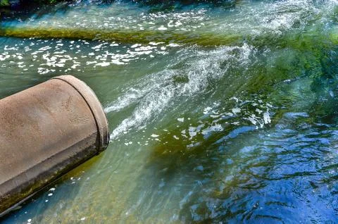 Water flows from the pipe into the river. Stock Photos