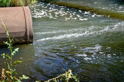 Water flows from the pipe into the river. Stock-Fotos