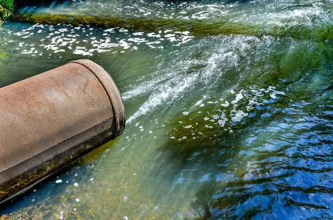 Water flows from the pipe into the river. Stock Photos