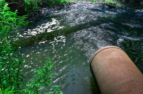 Water flows from the pipe into the river. Stock-Fotos