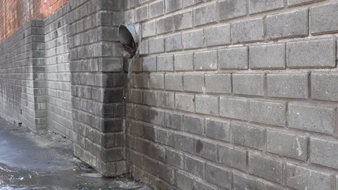 Water flows from a pipe in the wall to the street Stock Footage 124760647