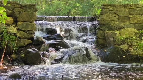 Water flows rapid through a small stone wall opeing Stock Footage 161817966