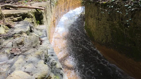 Water flows rapidly and creates a white foam when moving through a man-made Stock-Footage 335270677